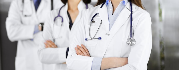 Group of professional doctors is standing as a team with arms crossed in clinic. Medicine concept during Coronavirus pandemic.