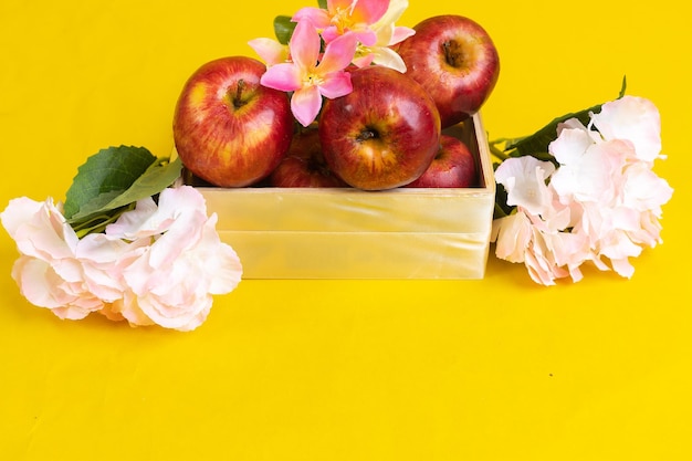 Group of red apples in wooden box on yellow background