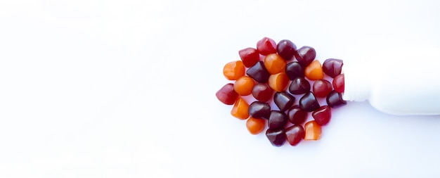 Group of red, orange and purple multivitamin gummies with the bottle isolated on white background. Healthy lifestyle concept.