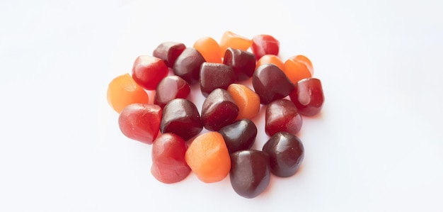 Group of red orange and purple multivitamin gummies with the bottle isolated on white background