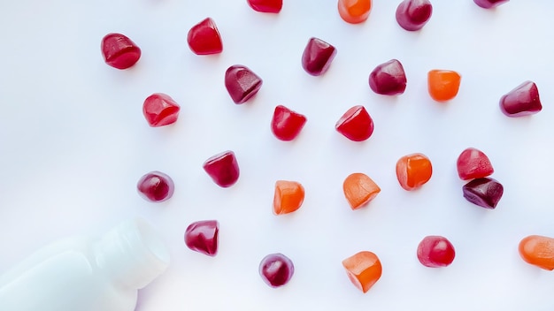 Group of red orange and purple multivitamin gummies with the bottle isolated on white background