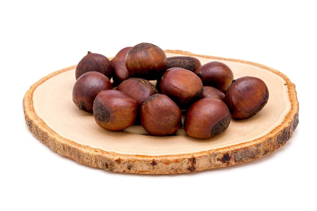 Group of roasted chestnuts on a wooden plate isolated on a white background