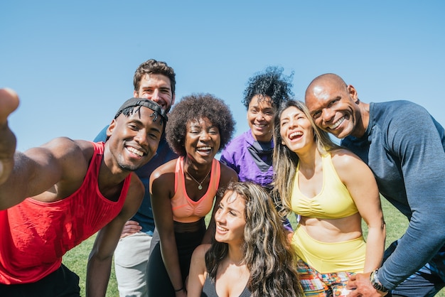 Group of runners taking a selfie in a park. Happy and smiling. Horizontal framing.