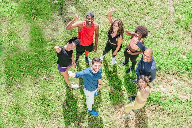 Group of runners waving at camera with raised fists. Top view. Horizontal framing.