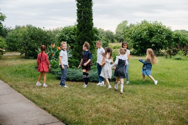 A group of school children runs in the Park in the summer. Happiness, lifestyle. Happy childhood.