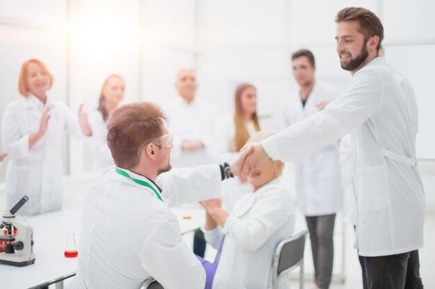 Group of scientists congratulating their colleague in the workplace