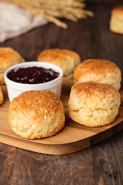 Group of scones on wood plate with jam on table