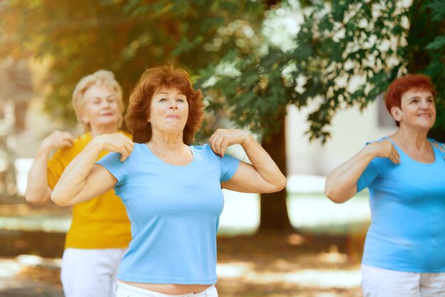 Group of senior people women training doing outdoor workout in city park on warm sunny morning Concept of sport and health active lifestyle age wellness body care