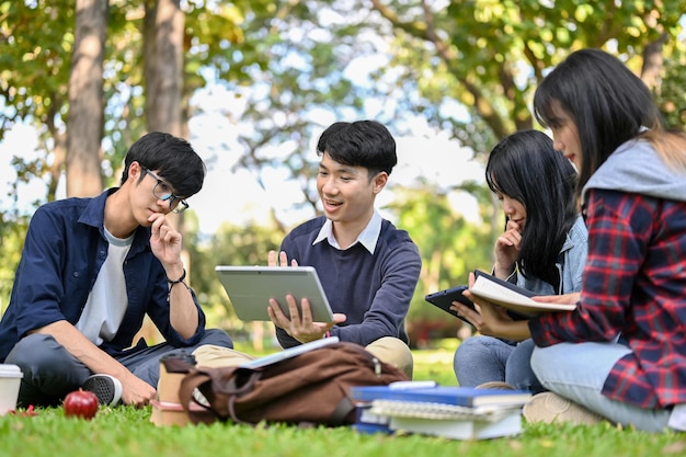 A group of smart young Asian college students doing their project together in the campus's park