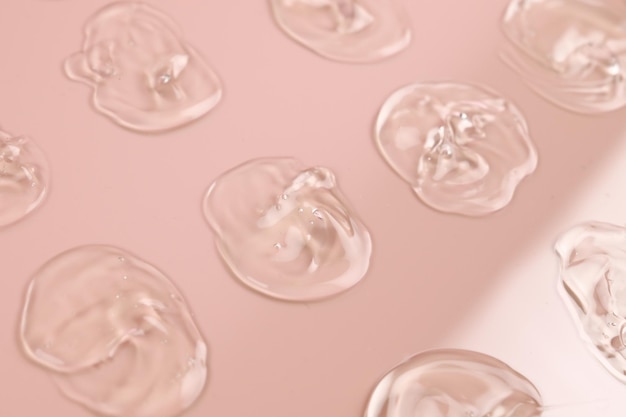 Group of smears of transparent gel on pastel pink background Hygiene skincare product creamy texture