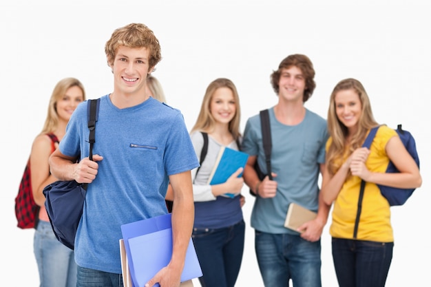 A group of smiling college students look into the camera as one man stands in front