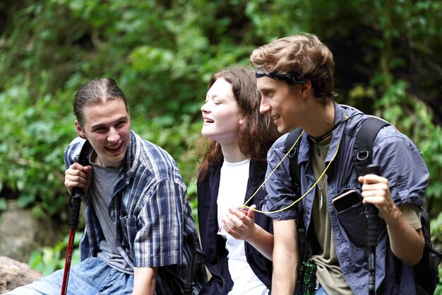 Photo group of smiling friends hiking with backpacks outdoors travel tourism hike and people concept