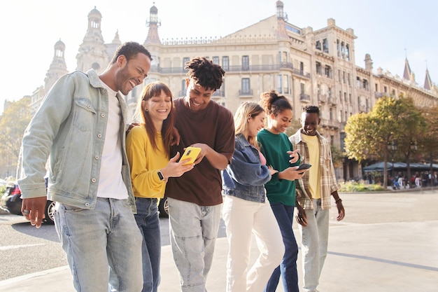 Group smiling multiracial young people using cell phones happy fellow university students outdoors