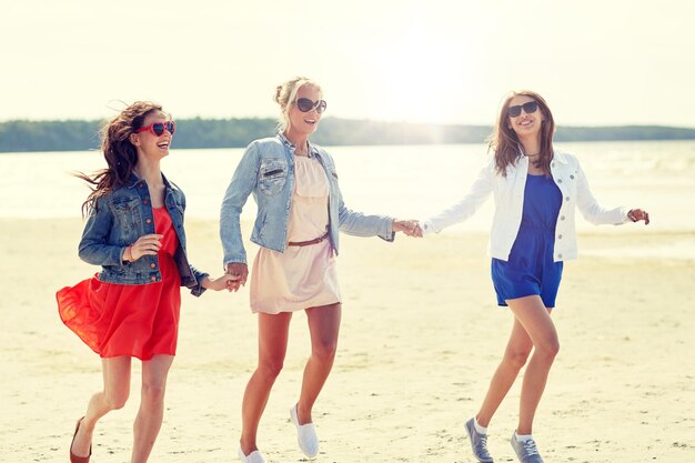 group of smiling women in sunglasses on beach