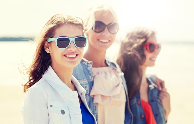 group of smiling women in sunglasses on beach