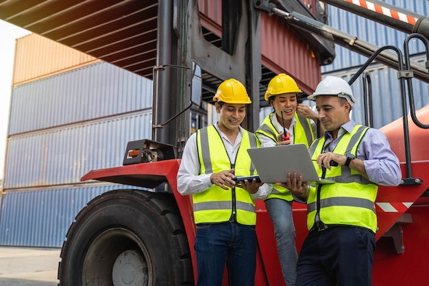 Group of staff worker standing and checking the containers box from cargo ship for export and import