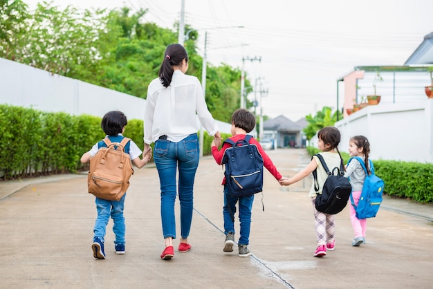 Group of student and teacher holding hands and walking to home