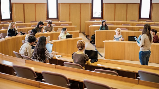 Group of students in a circular classroom with the teacher explaining the lesson