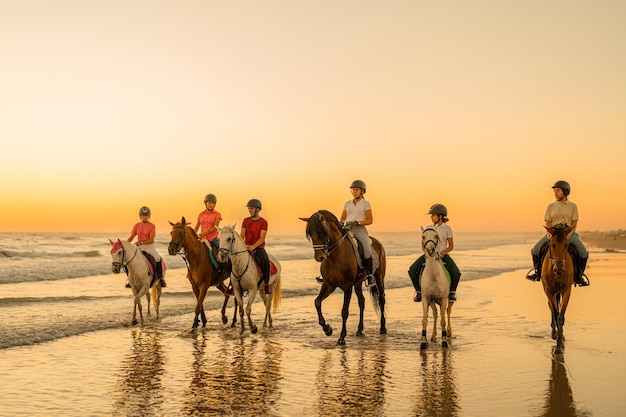 Group of students of an equestrian school walking with their horses along the seashore