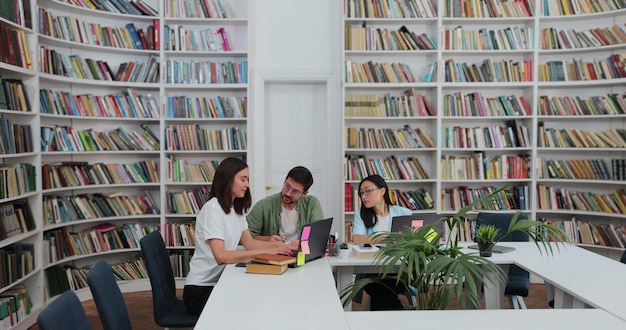 Group of students preparing for exam in university library Happy diverse students talking learning studying together for exams Education concept