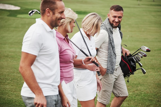 Photo group of stylish friends on the golf course learn to play a new game. the team is going to rest after the match