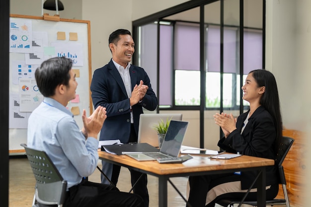 A group of successful Asian businesspeople are clapping their hands and celebrating their successful