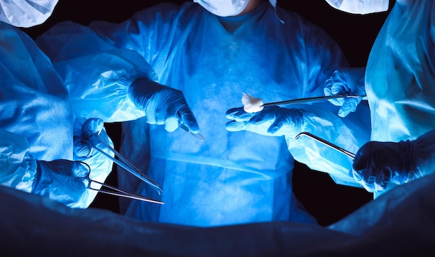 Group of surgeons wearing safety masks performing operation. Medicine concept.