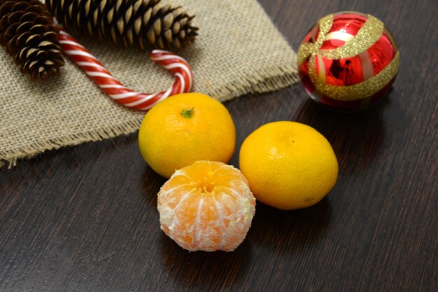 group of tangerines with pine corns, christmas sphere and candy, close-up