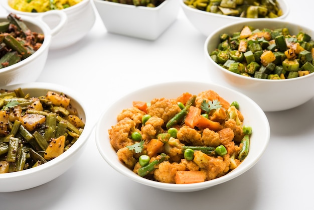 Group of Tawa fry sabzi or sabji like cauliflower or Phool Gobhi, bhindi OR okra, Gwar OR Cluster Beans, French Beans, Cabbage or Patta Gobi, Flat Green Beans, served in a bowl. selective focus