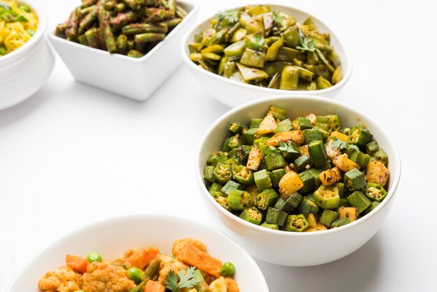 Group of Tawa fry sabzi or sabji like cauliflower or Phool Gobhi, bhindi OR okra, Gwar OR Cluster Beans, French Beans, Cabbage or Patta Gobi, Flat Green Beans, served in a bowl. selective focus