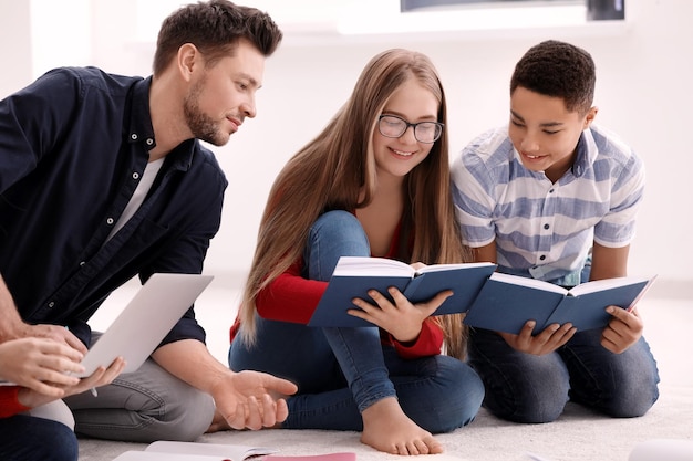 Group of teenagers doing homework with teacher indoors