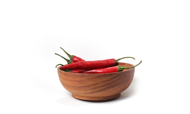 Group of three chili peppers in a wooden bowl