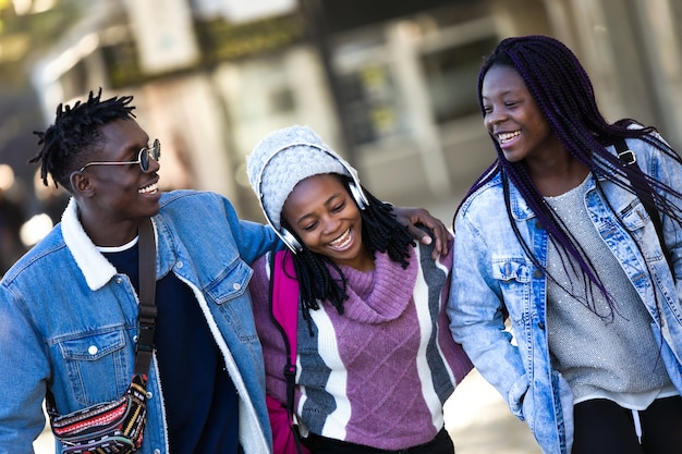 Group of three friends walking and laughing in the street.