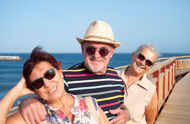 Group of three happy smiling senior people enjoy sea excursion in summer vacation