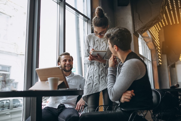 Group of three people working on a project on a tablet in a cafe