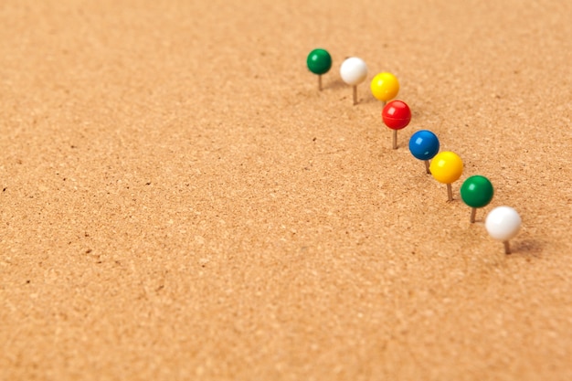 Group of thumbtacks pinned on corkboard