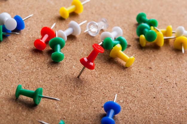 Group of thumbtacks pinned on corkboard