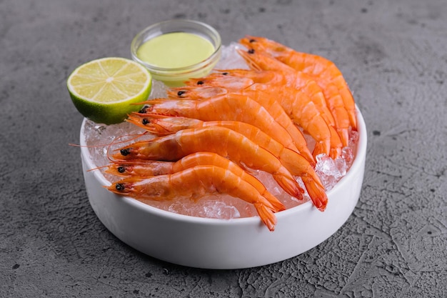 A group of tiger shrimp on a bowl of ice with lime