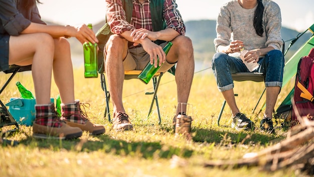 group of tourists clinking beer bottles in camping.adventure, travel, tourism, friendship and people concept.