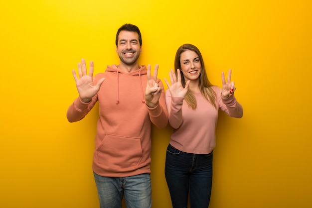 Group of two people on yellow background counting seven with fingers