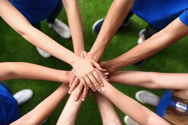 Group of volunteers joining hands together outdoors top view