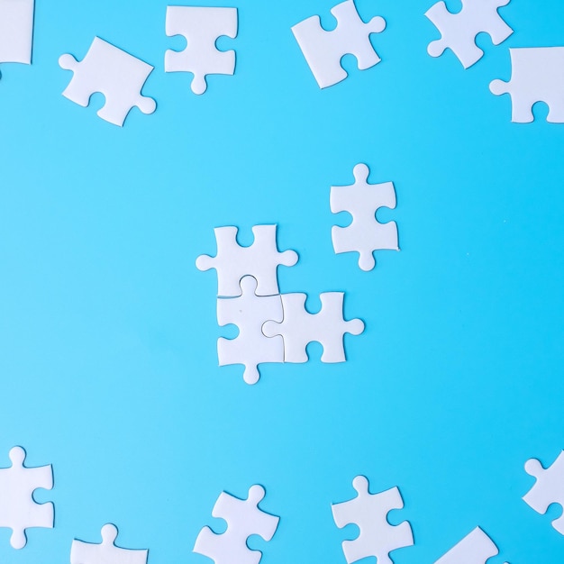 Group of white puzzle jigsaw pieces on blue background Concept of solutions mission success goals cooperation partnership strategy and puzzle day