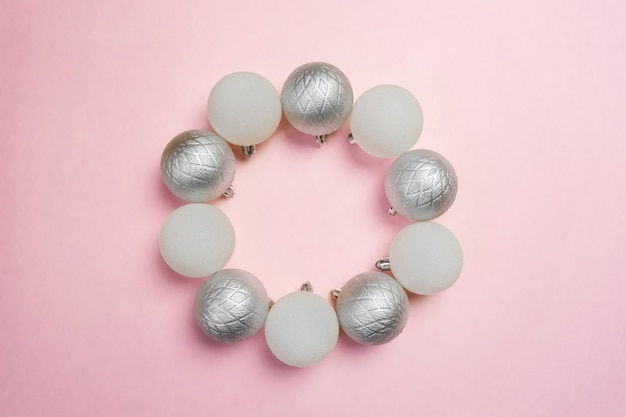 Group of white and silver ornaments put in circle on pink