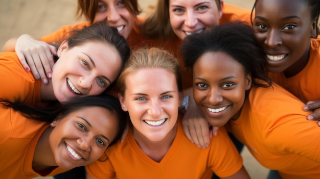 A group of women wearing orange shirts are smiling and hugging each other