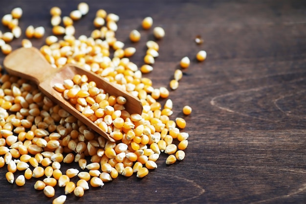 Group of yellow raw corn kernels sweet corn. Grain seeds ingredient golden maize kernel. Wooden table ripe popcorn background.