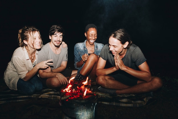 Photo group of young adult friends sitting around the bonfire