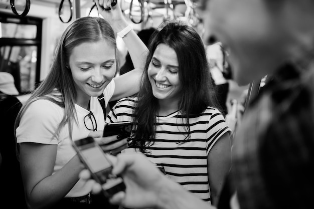 Group of young adult friends using smartphones in the subway