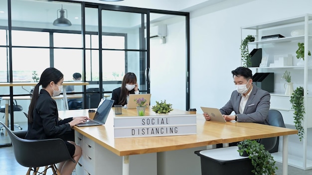 Group of young Asian team business people with face masks work in office