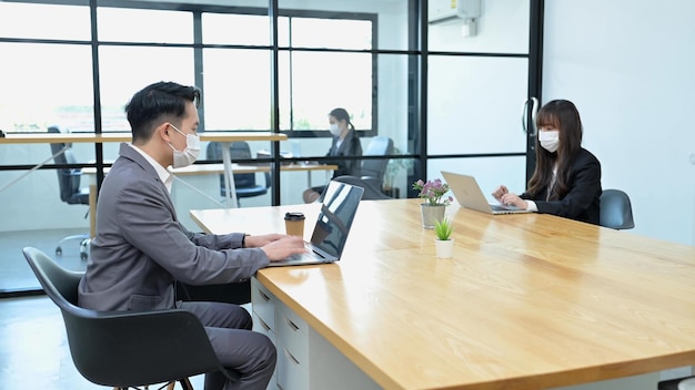 Group of young Asian team business people with face masks work in office