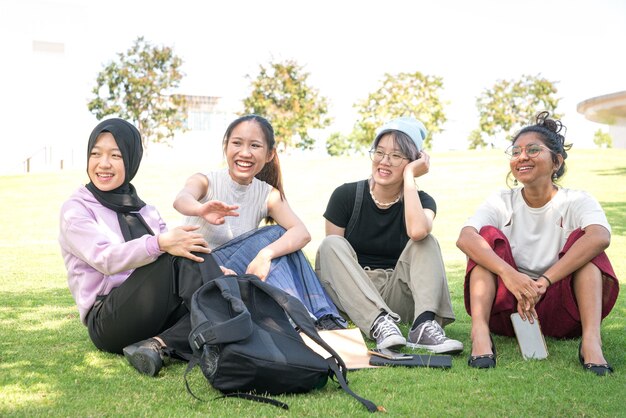 Group of young Asian women sitting on green lawn talking and laughing